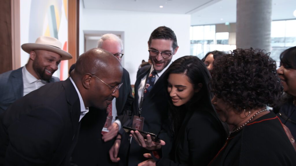 Van Jones, Kim Kardashian, Alice Johnson, Louis L. Reed and 
Alex Guditch of #cut50 huddle over acell phone to watch president Trump deliver a speech on the First Step Act in a scene from THE FIRST STEP. Image courtesy of Meridian 