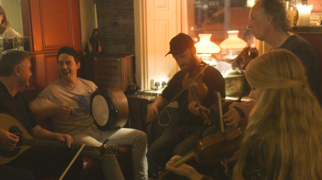 A group of musicians sit in a warm pub playing music and laughing. 

Location: Fitz’s Pub in Doolin, County Clare, Ireland 

Left to right: Eoin O’Neill, Kieran O’Connell, Adam Shapiro Christy Mc Namara, Beth Tipton 

Photo credit: Anika Kan Grevstad 